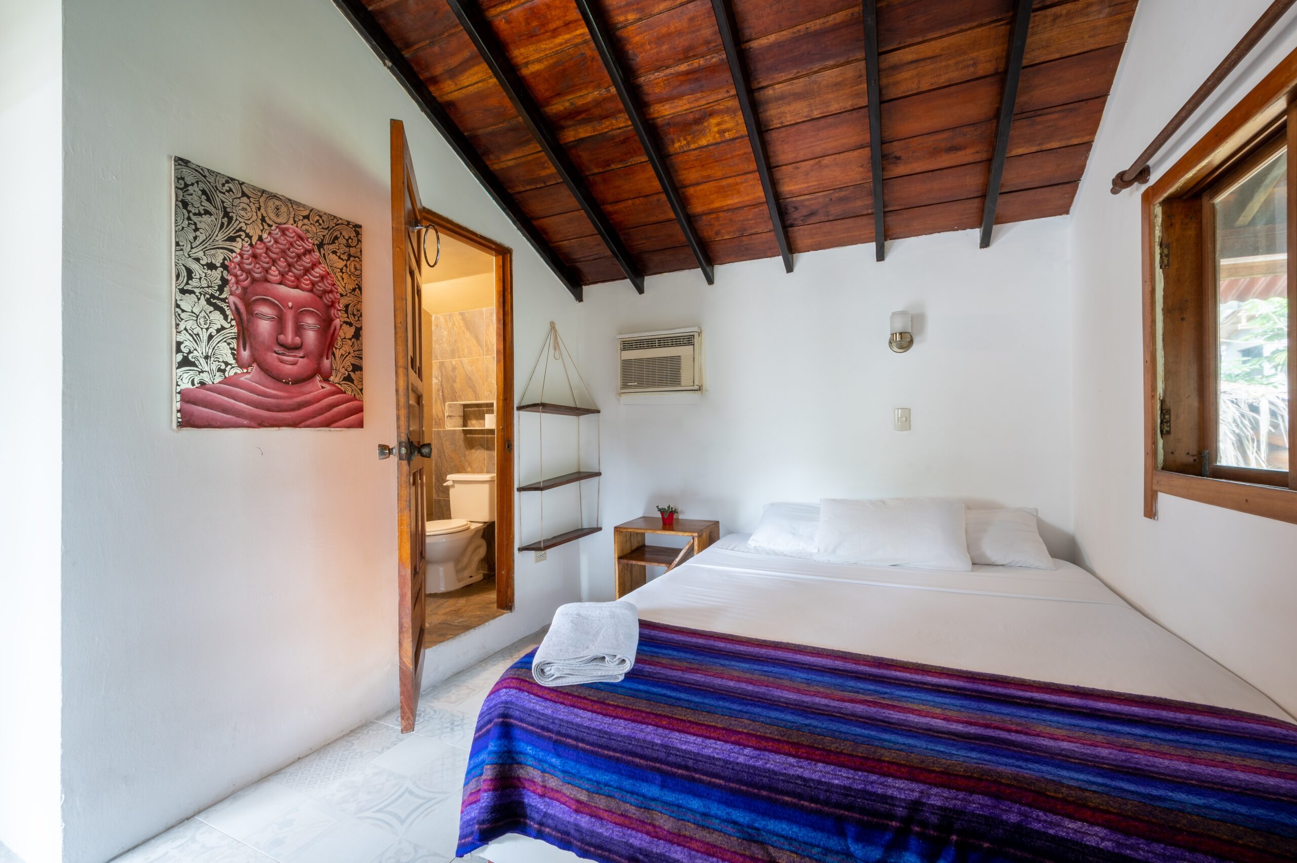 Cozy bedroom interior with Buddha artwork and colorful blanket