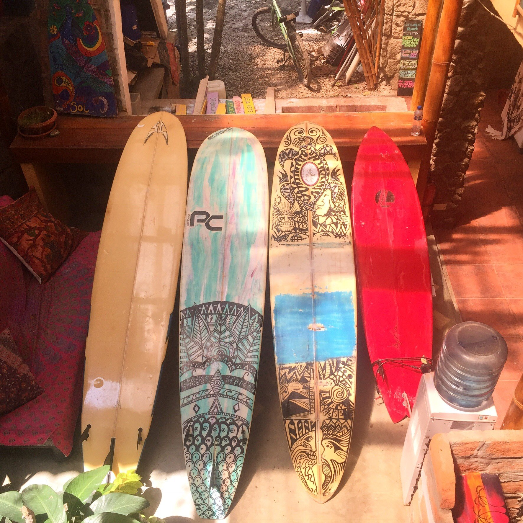 Four colorful surfboards leaning against a wooden wall